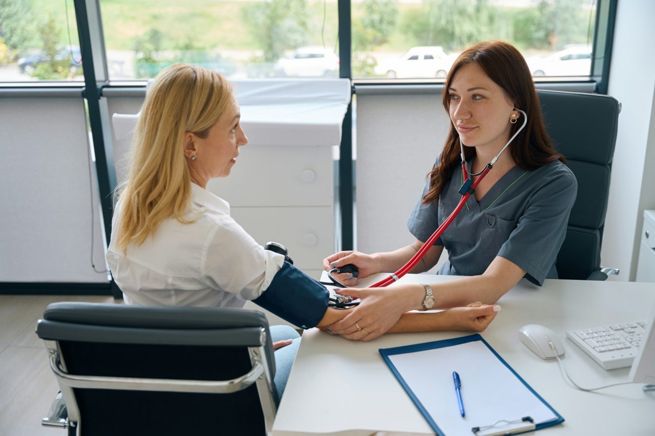 Adult woman undergoing routine health check with family doctor