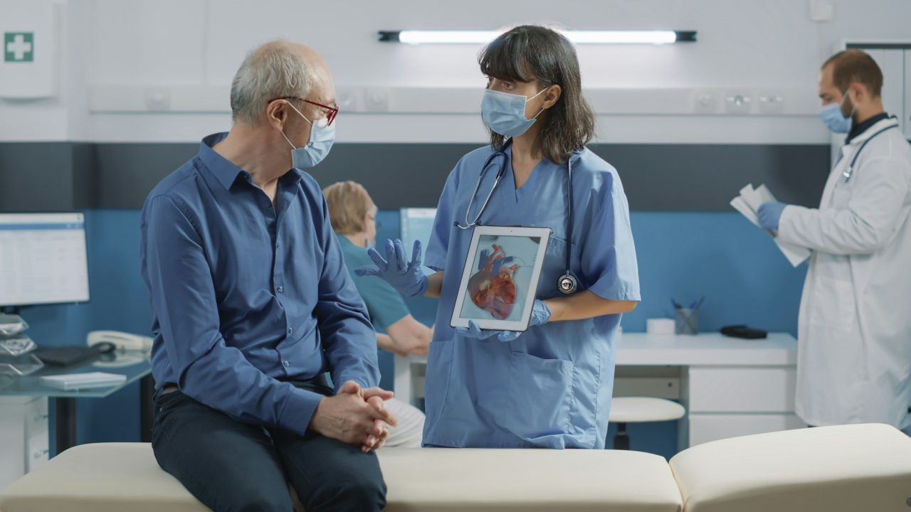 Nurse and elder patient looking at cardiology illustration